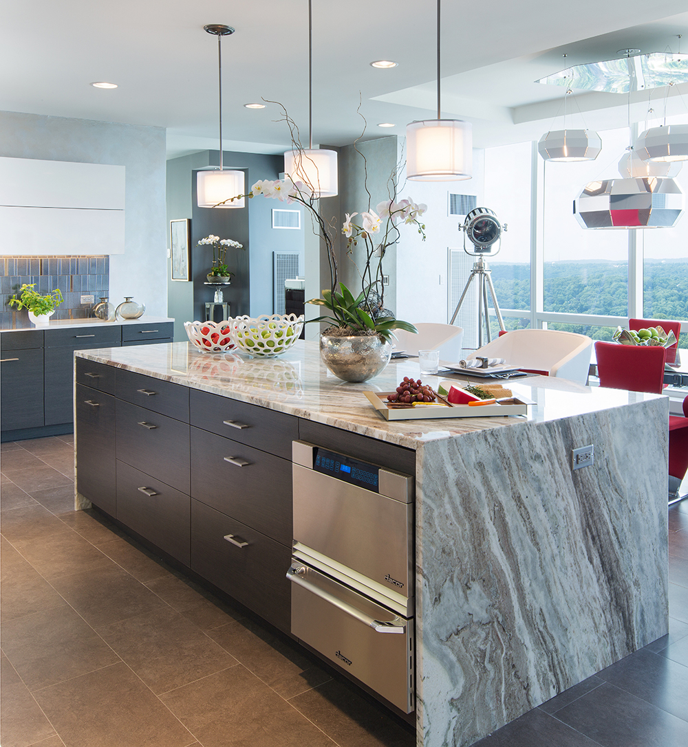 A kitchen featuring grey and white granite countertops with darker cabinets